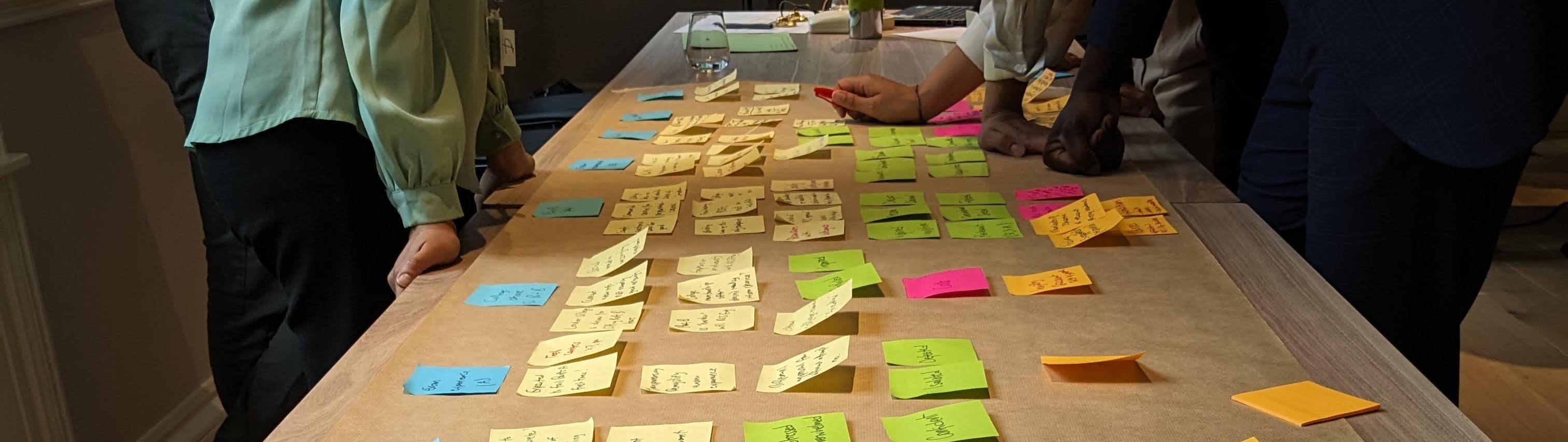 People arranging coloured sticky notes on a table to tell a story